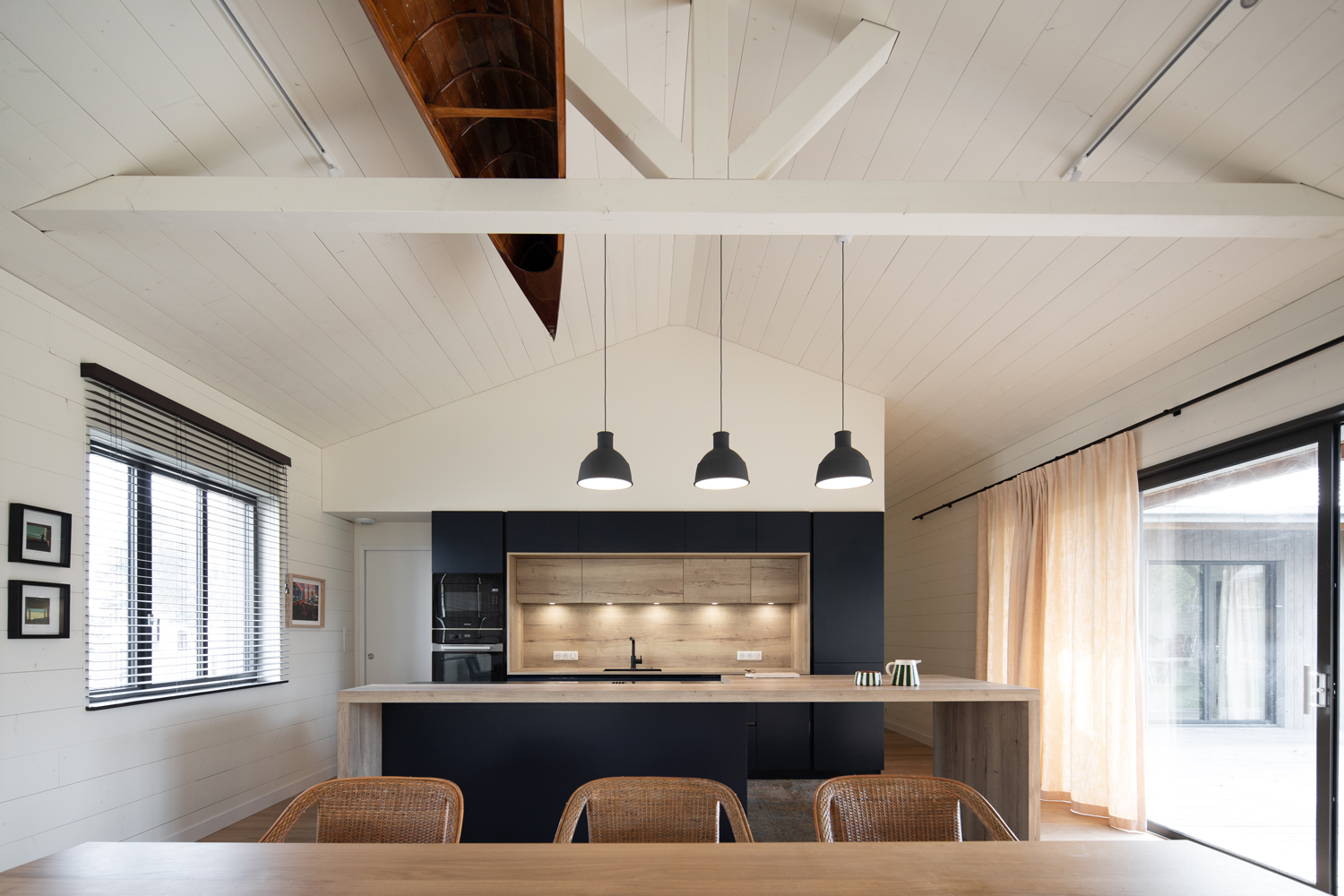 Création d’une maison individuelle et de son annexe. Maison en ossature bois avec intérieur en bois. Lambris blanc. Ilot de cuisine sur mesure. Parquet au sol. Grandes baies vitrées à galandage. Poutres apparentes. Stores à lames sur fenêtres