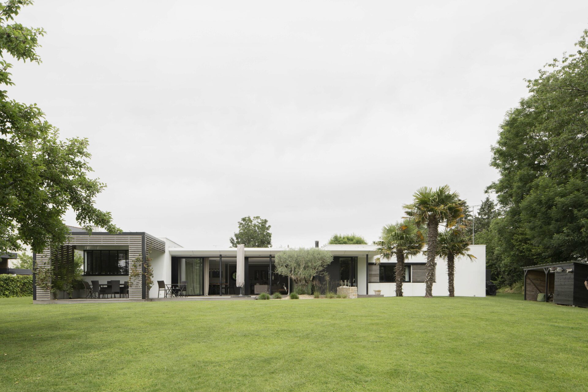 Création d'une maison individuelle de plain pied en bardage bois. Casquette en aluminium blanc avec poteau noir et spots intégrés. terrasse en bois. Grandes baies vitrées. Pergola en bois.